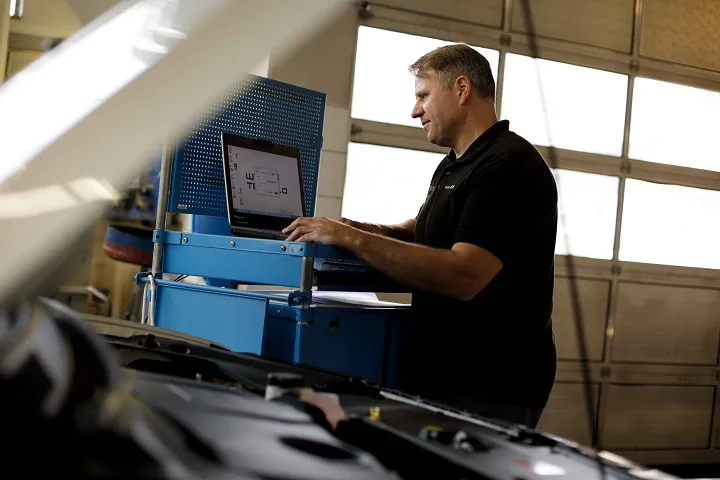 Mechaniker bei der Fahrzeugdiagnose mit einem Laptop
